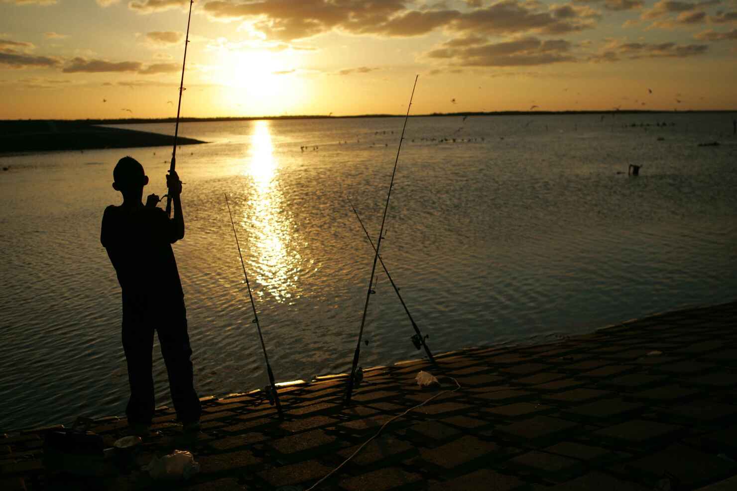 Young_man_stands_fishing_at_sunset.jpg